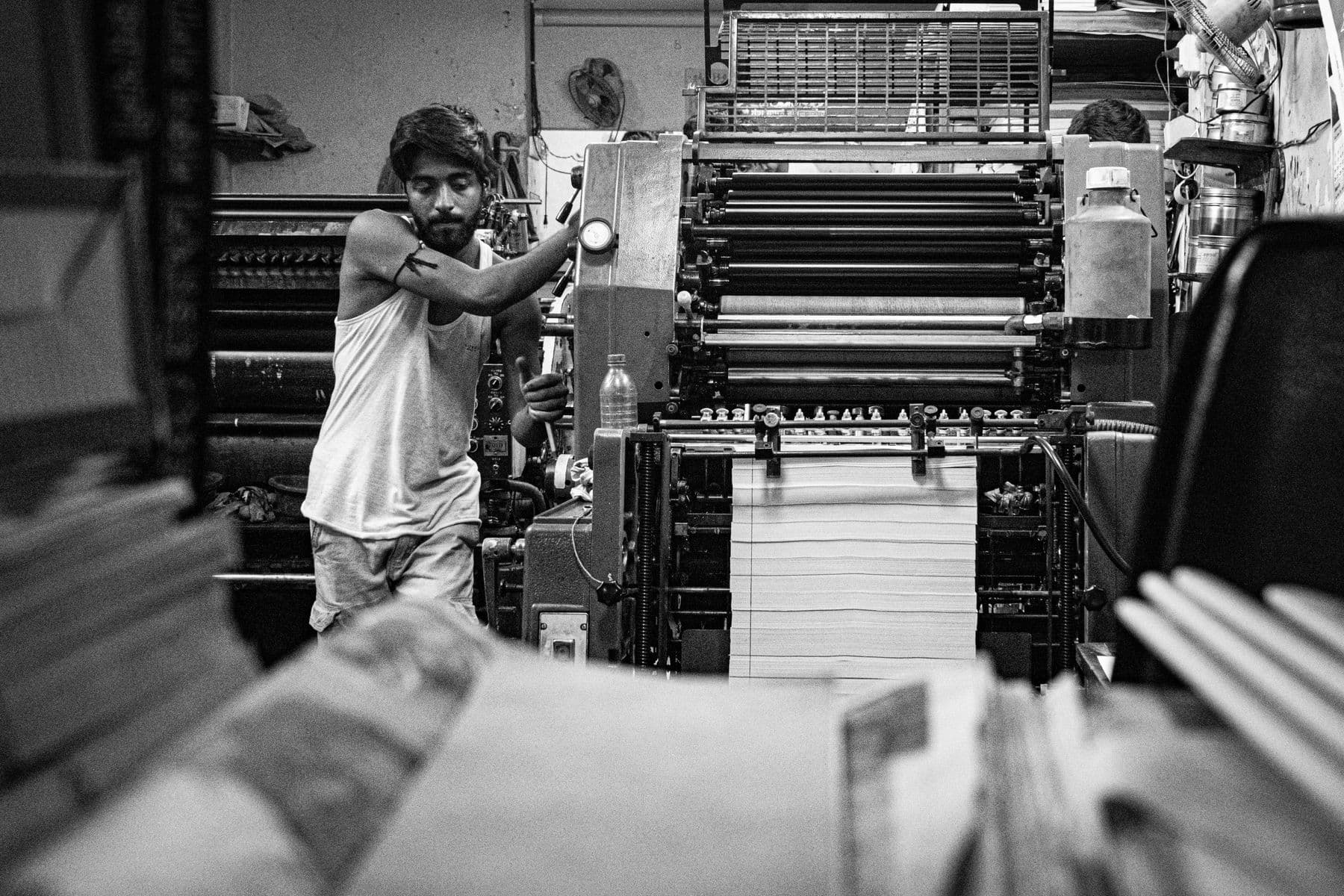 Press operator running sheets through an offset press